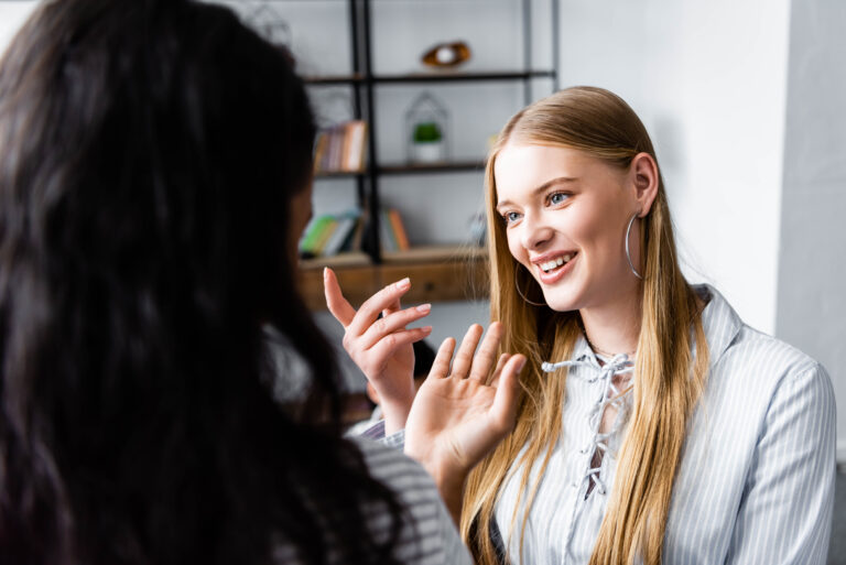 selective focus of multicultural friends smiling and talking in apartment